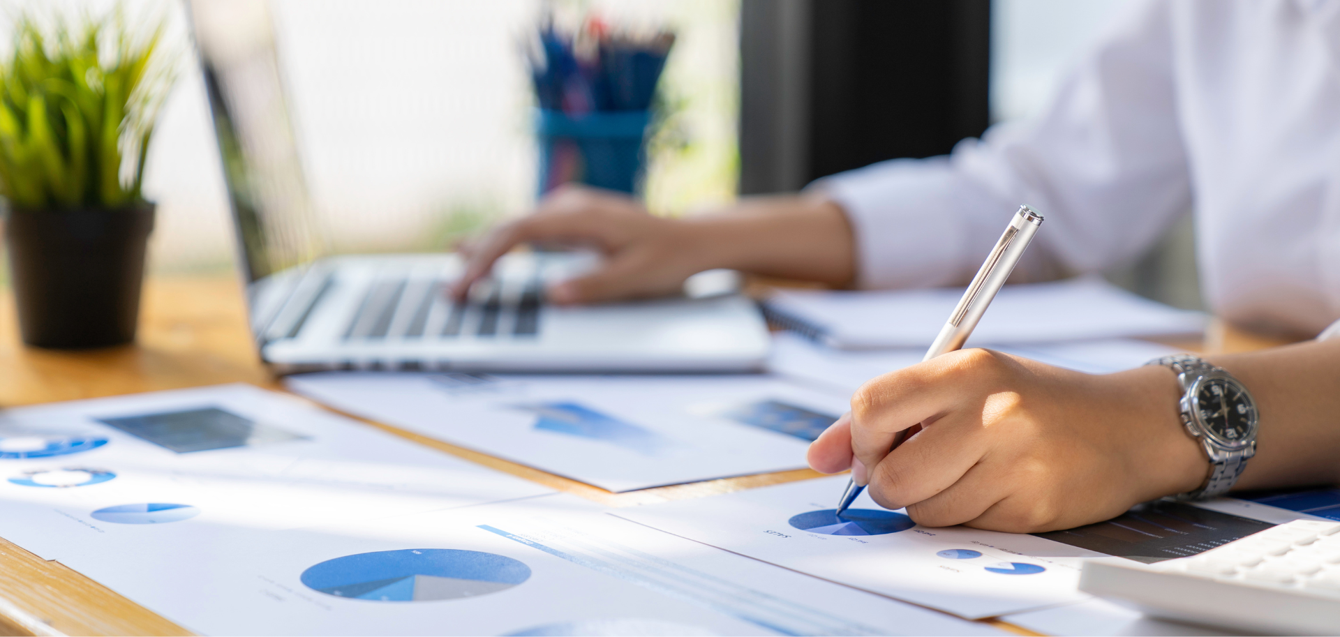 Profissional analisa gráficos e relatórios financeiros em mesa de trabalho, representando o planeamento fiscal estratégico.