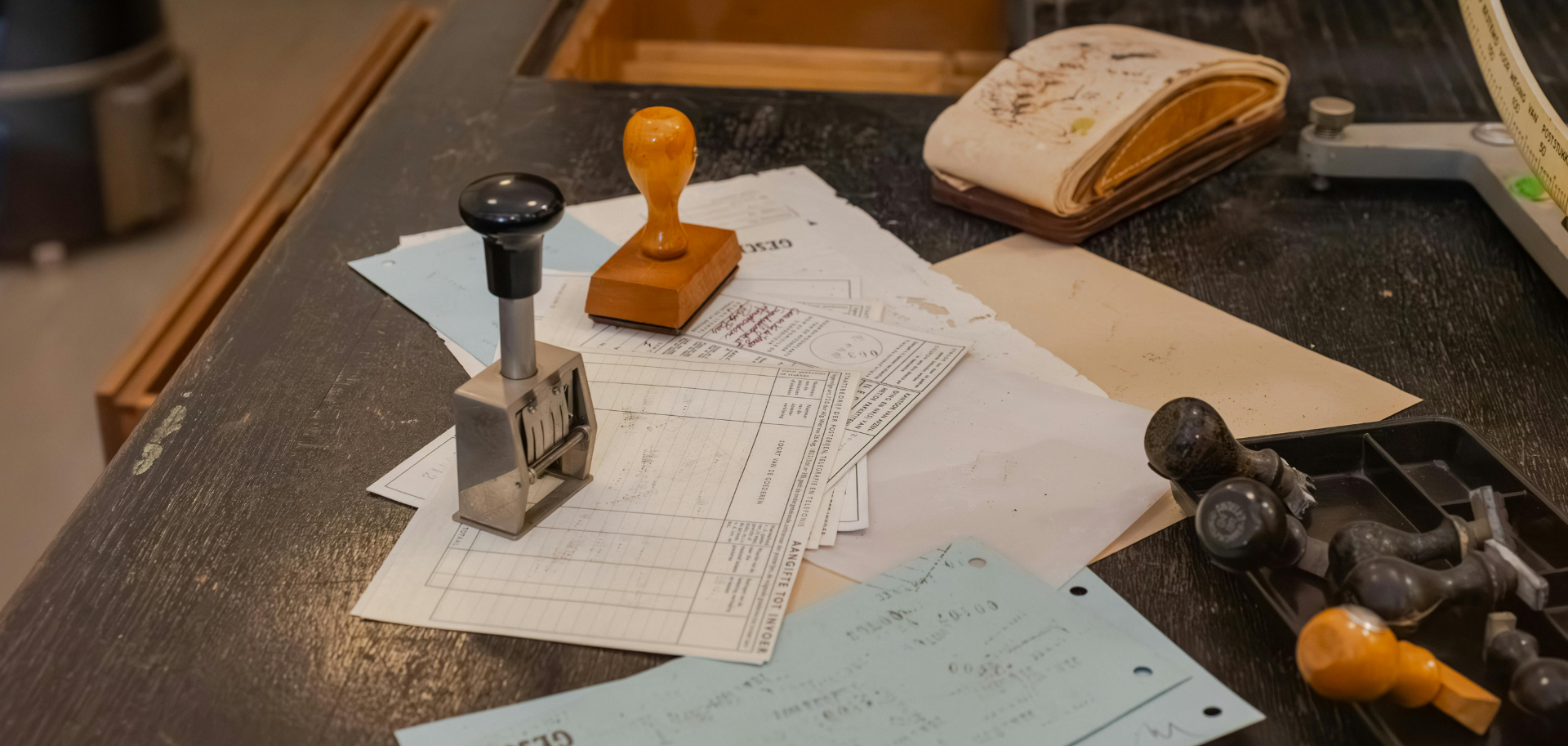 Mesa de trabalho com documentos, carimbos e formulários, representando processos administrativos e autorizações públicas