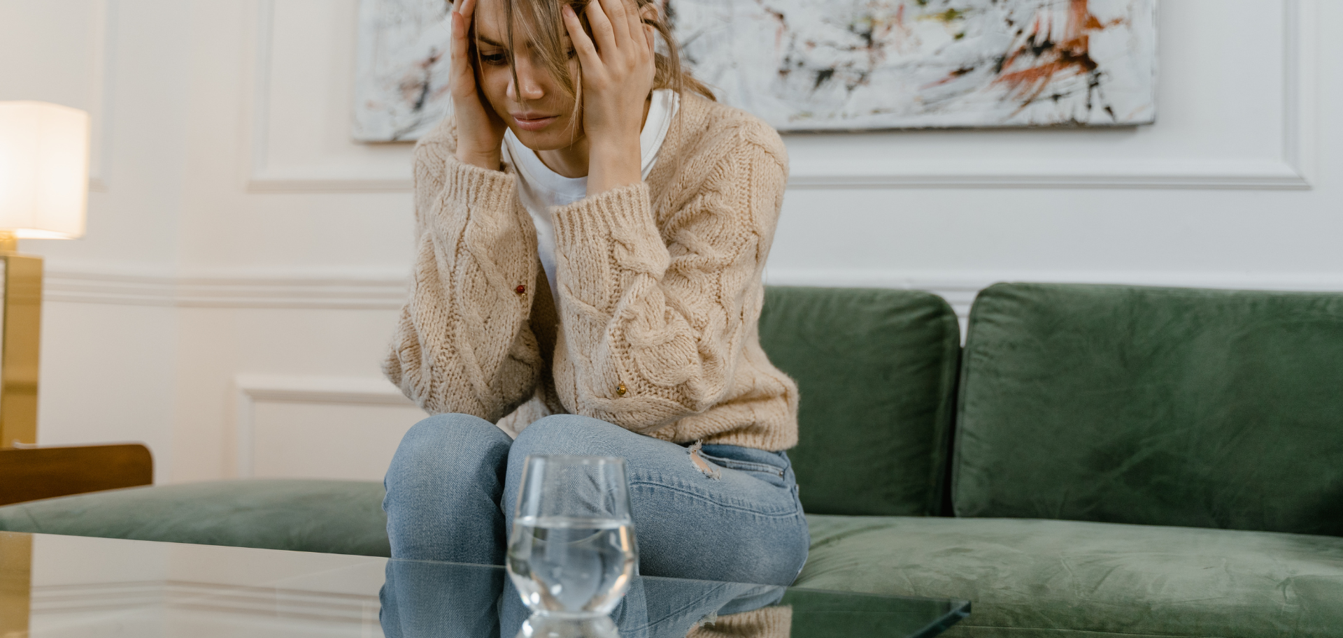 Mulher sentada no sofá com expressão preocupada, representando situação de violência doméstica
